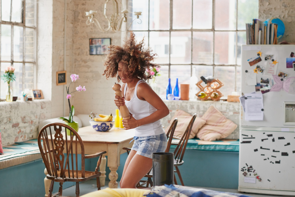 Happy curly haired girl dancing in kitchen