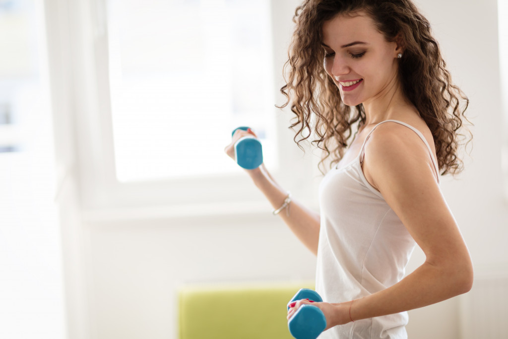 woman lifting dumbbells in her house