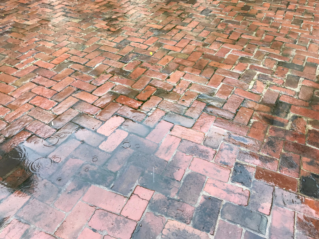 rain falls on ground red brick pavement