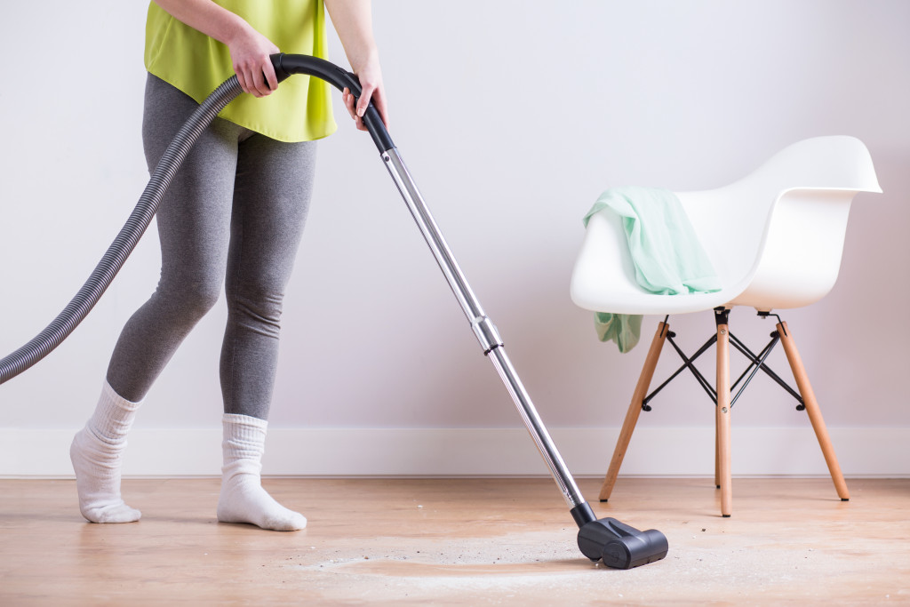 Close-up of woman vacuuming the dust of the floor