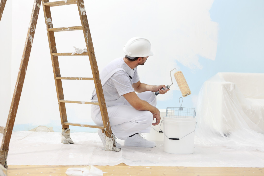 A worker repainting a blue wall white