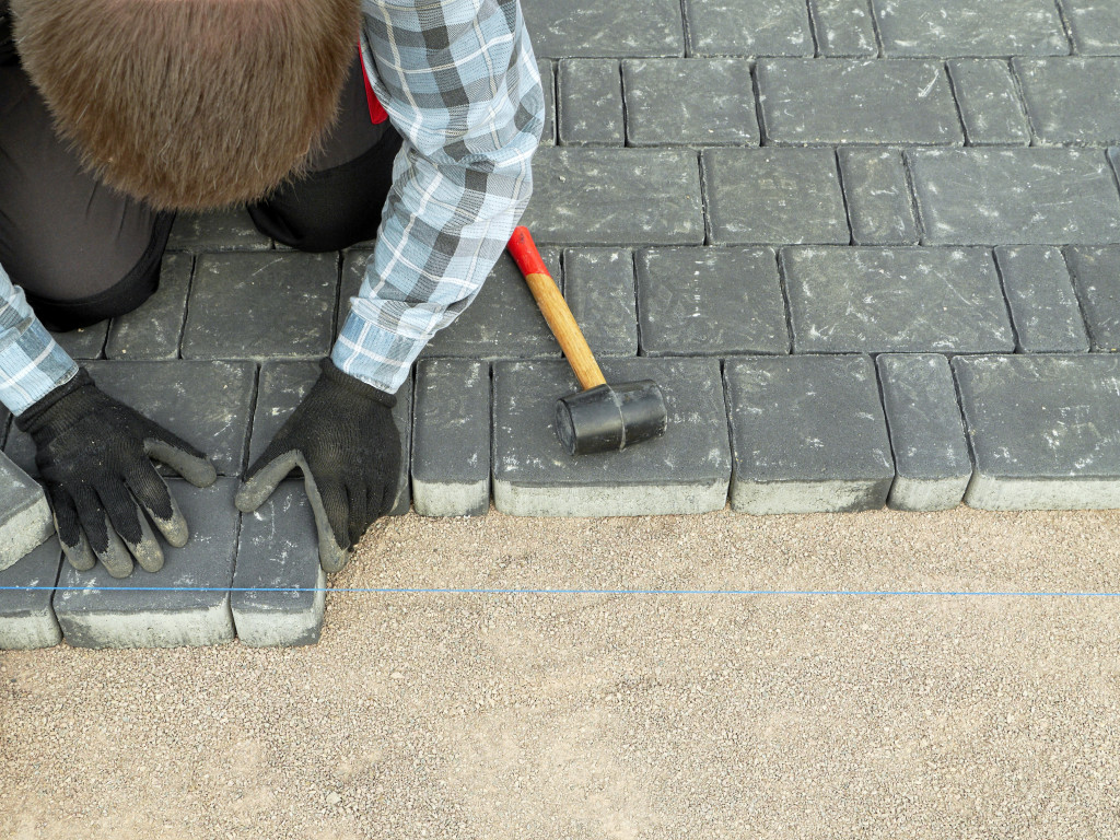 a worker aligning concrete driveway blocks