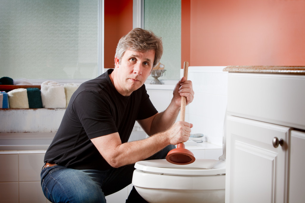 A man unclogging a toilet using a plunger
