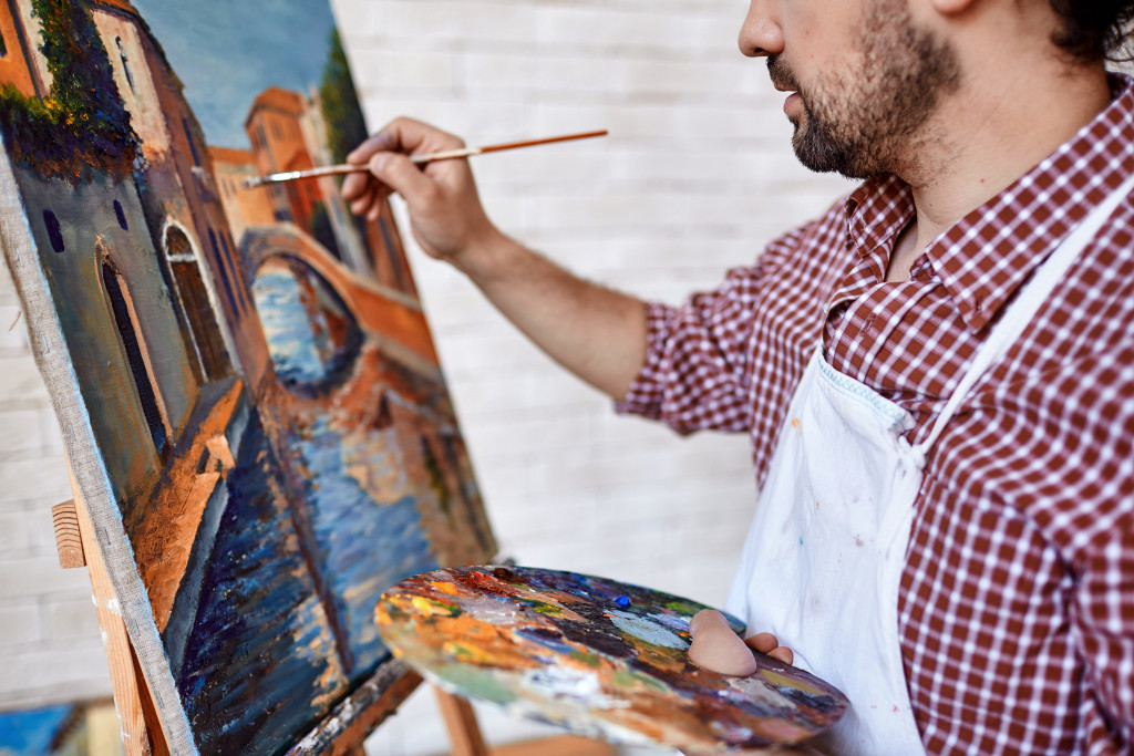 Modern artist painting landscape with oil paints
