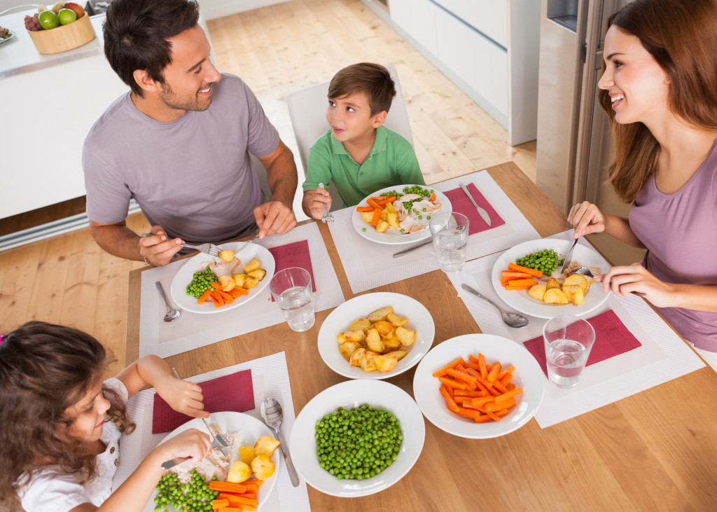 A family of four - father, mother, son, and daughter are eating together at the family table.