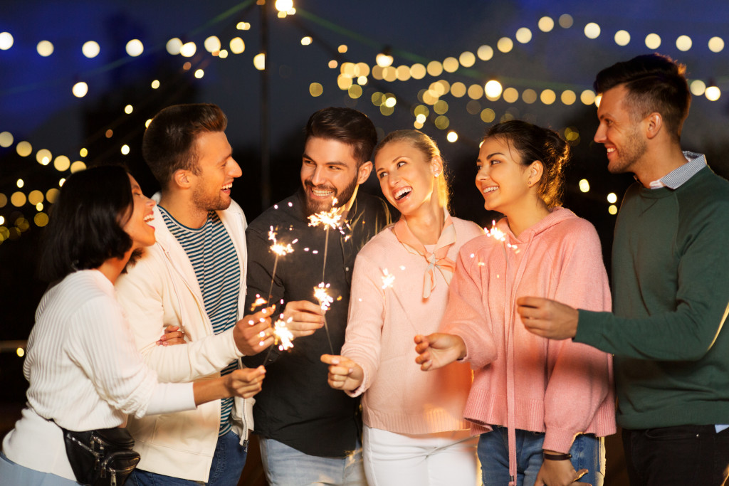 a group of friends holding sparklers while outdoors