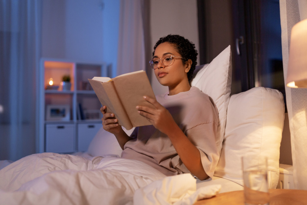 a woman in bed reading a book at night