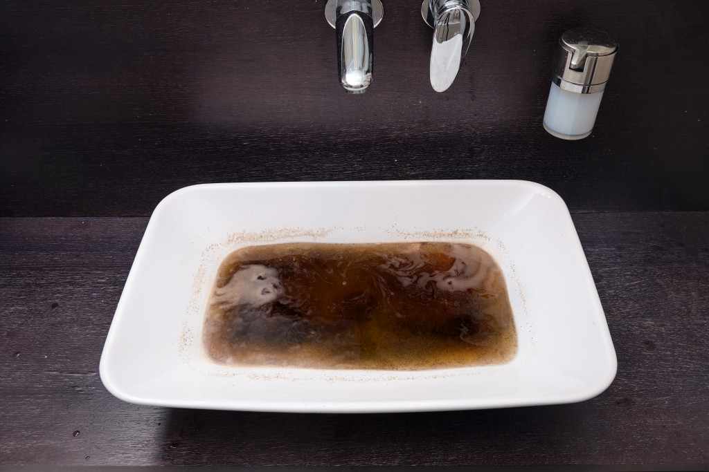 Blocked bathroom sink, filled with dirty water