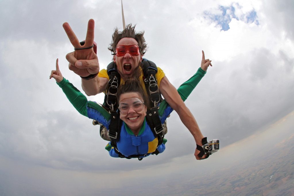 man and woman smiling while skydiving in tandem