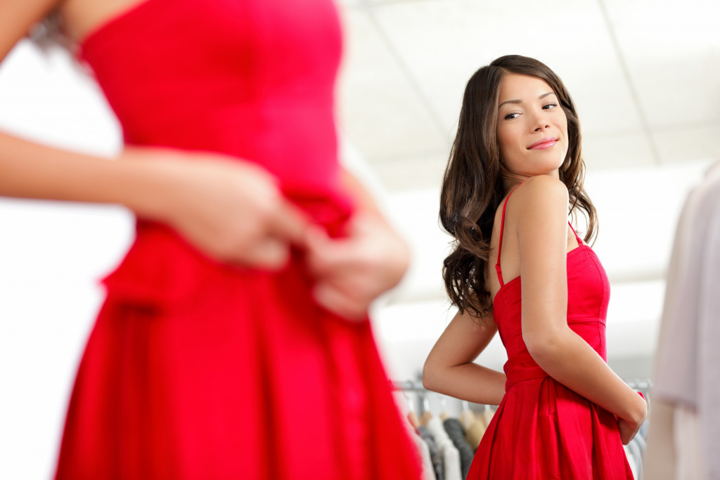 A woman looking at the mirror, trying a new red dress