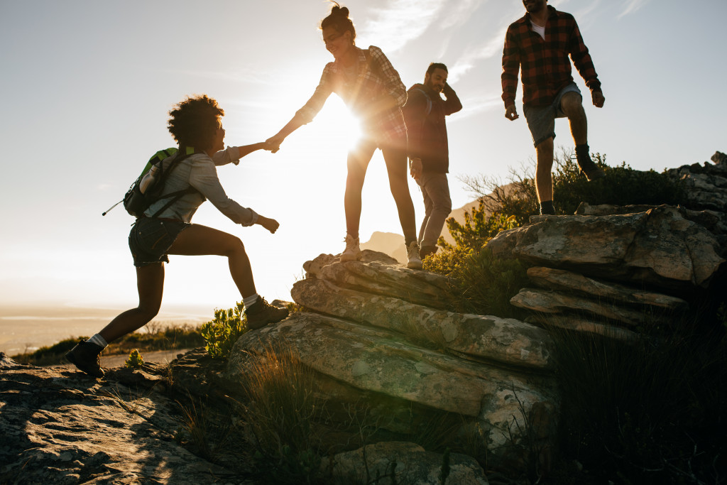 friends helping each other climb a mountain in the sunrise