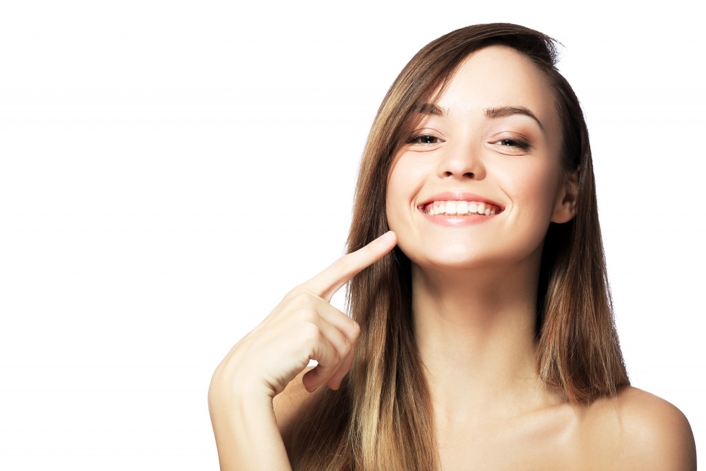 woman smiling pointing to her teeth