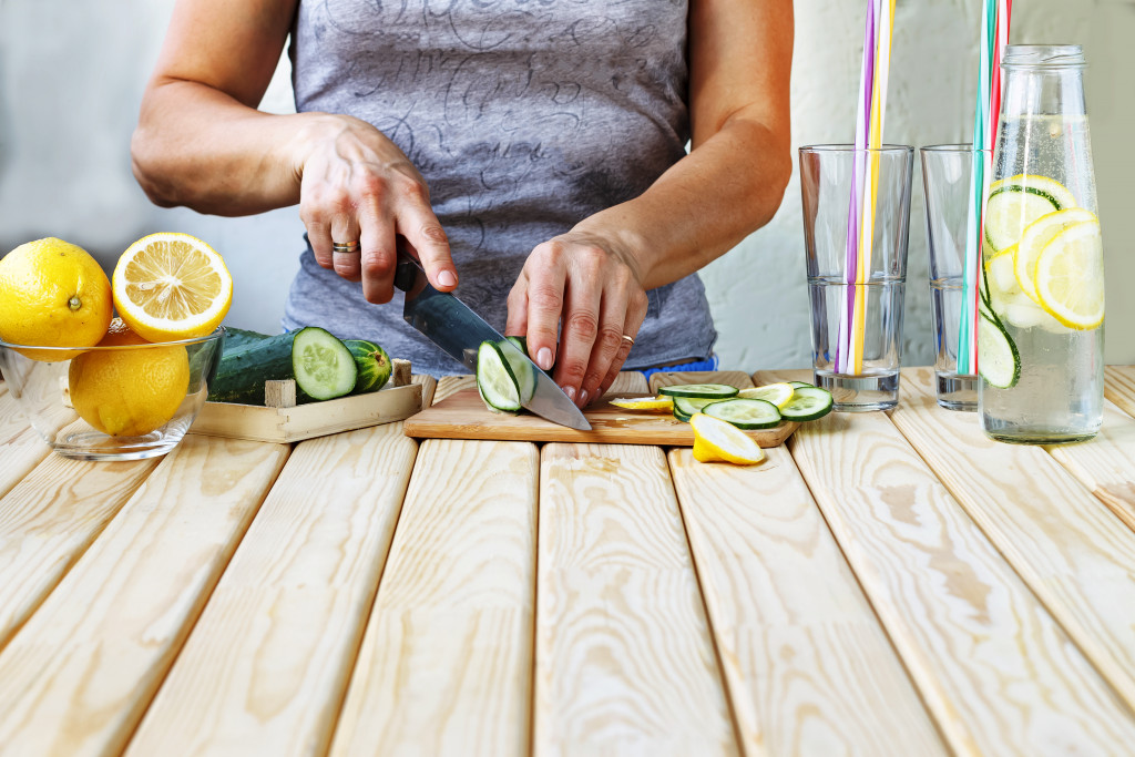 A person slicing citrus fruits to put in water