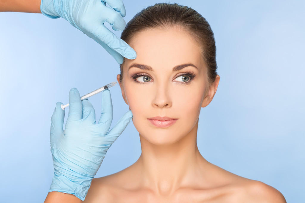 woman being injected in her eye wrinkles by a person in gloves