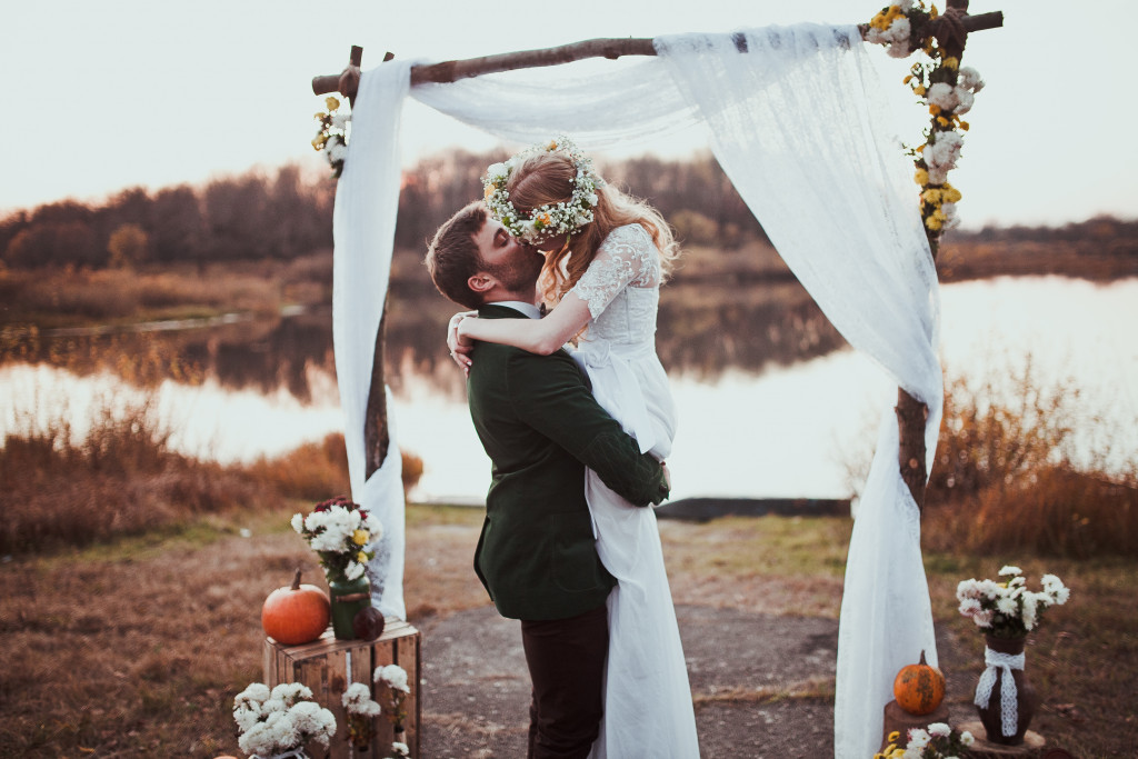 Newlyweds kissing beside a lake