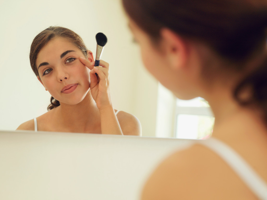 A teenager applying makeup to herself