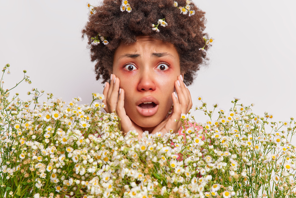 curly haired woman having allergic reaction to flower pollens