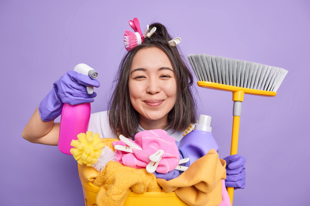 A happy woman holding different cleaning tools