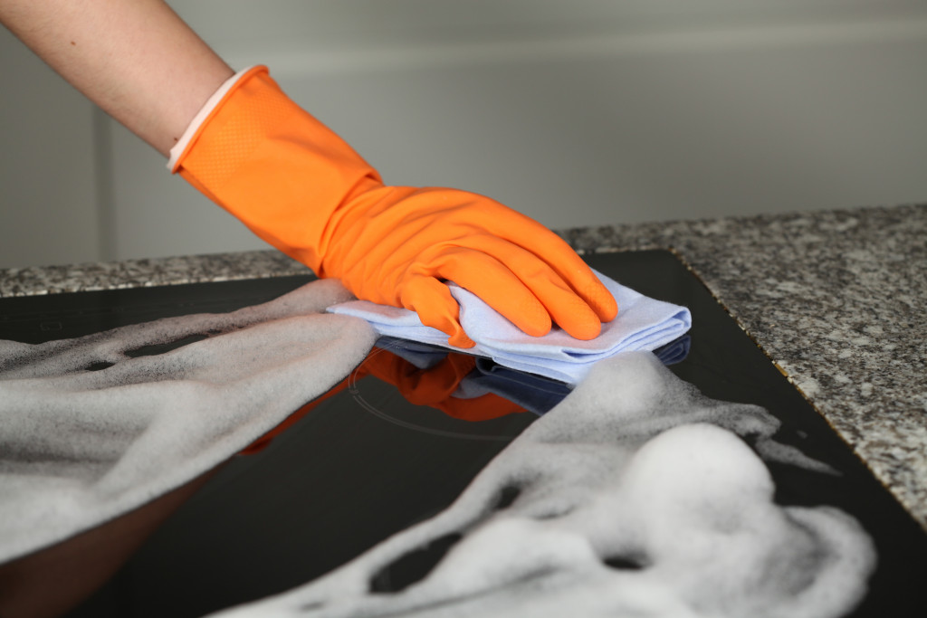 A hand cleaning a stove top