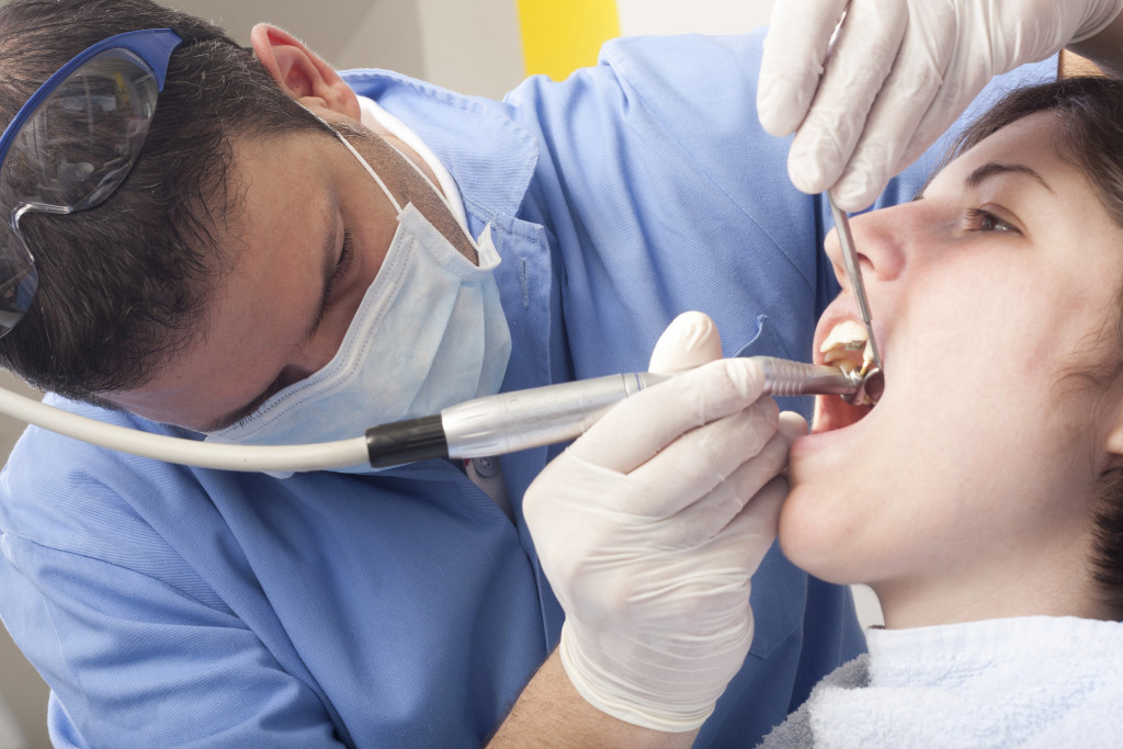 A dentist cleaning a patient's teeth in the clinic