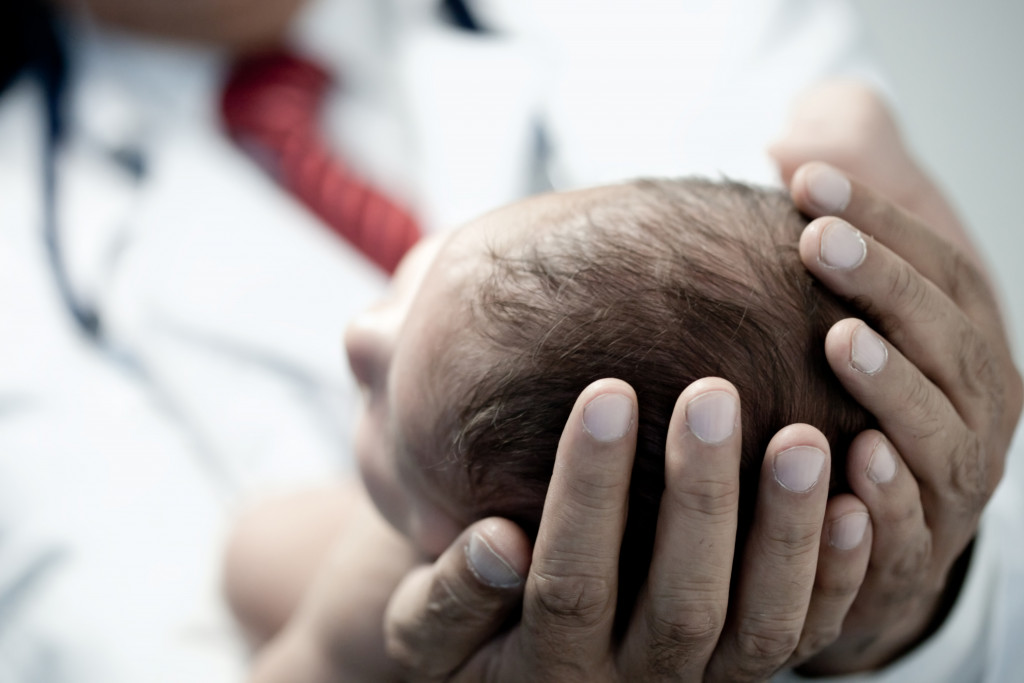 doctor holding a baby head close up