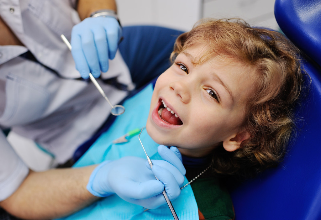 red-haired boy smiling while getting checked at the dentist