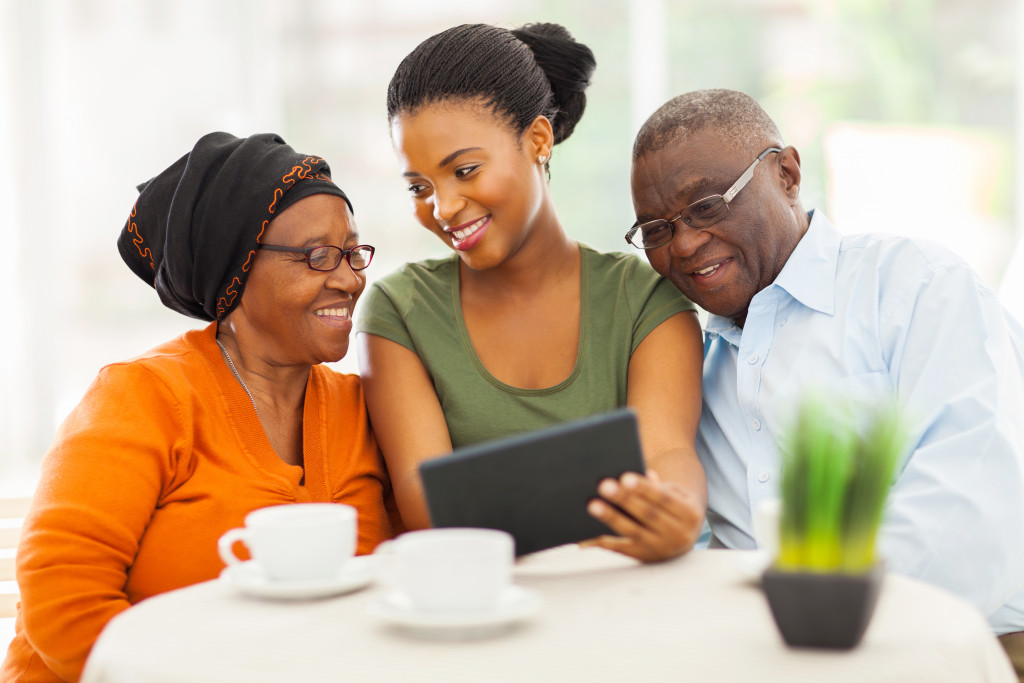 woman talking to elderly parents teaching them tablet