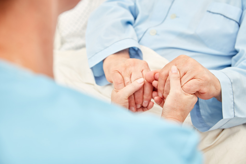 female nurse holding a patient's hands in a hospice