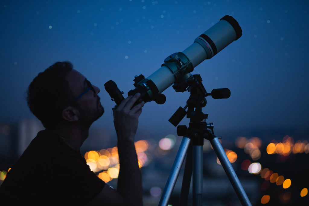 Young man observing the skies using a telescope.